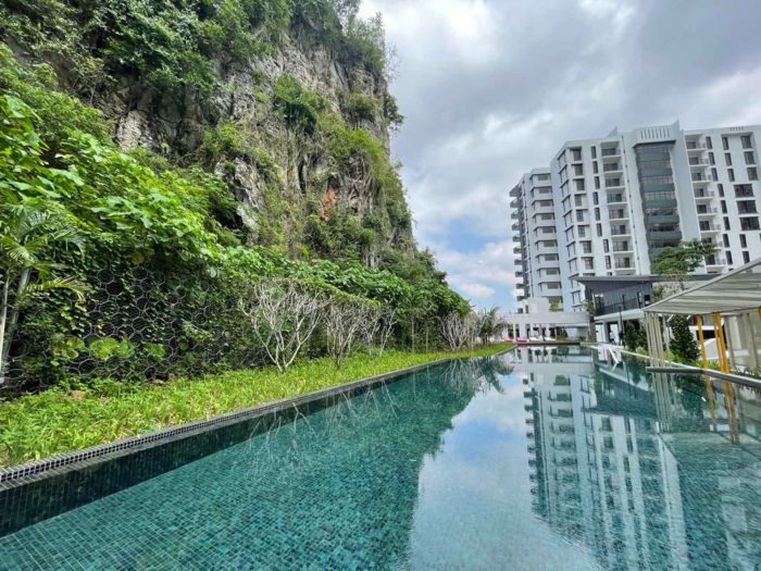 Limestone cliff with protective netting beside a resort swimming pool