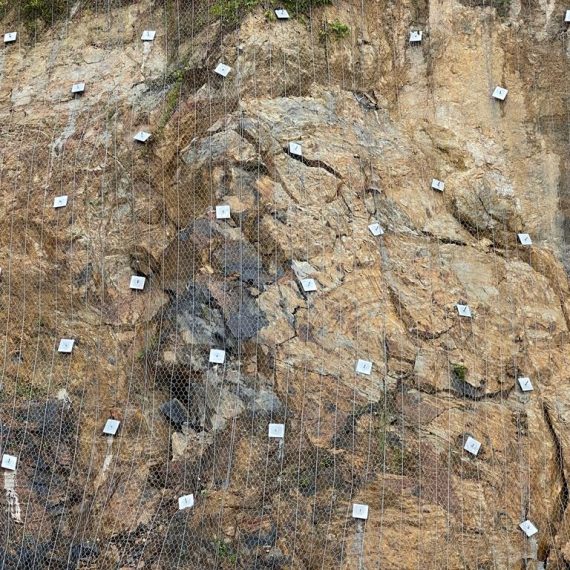 Close-up of anchored wire mesh netting stabilizing a rock slope face
