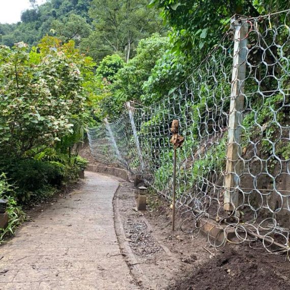 Ring net rockfall barrier fence installed along a hillside pathway