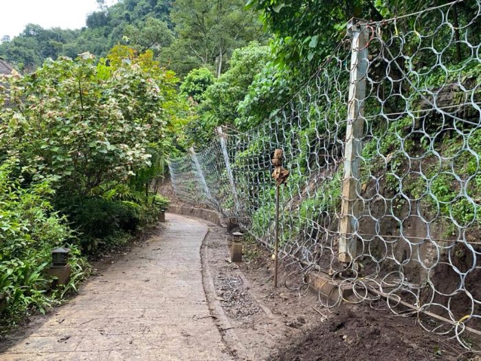 Ring net rockfall barrier fence installed along a hillside pathway
