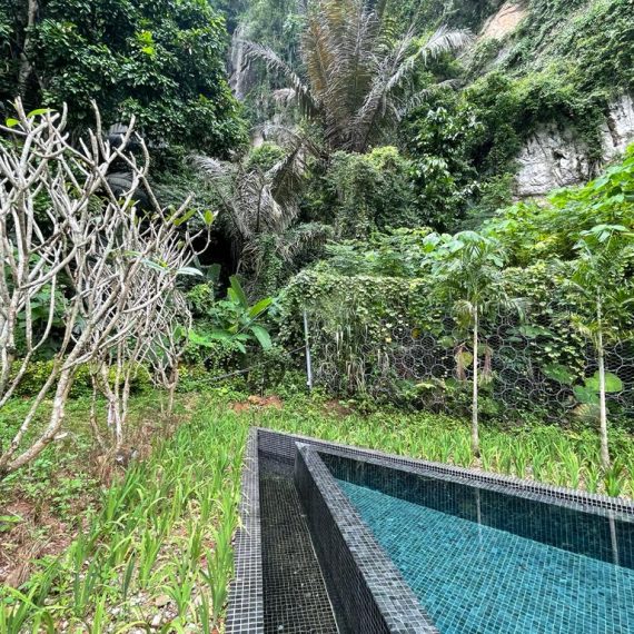 Rockfall protection mesh on a limestone cliff face beside a resort pool